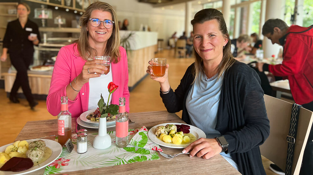 Zwei Damen sitzen an einem Tisch und genießen ihr Mittagessen