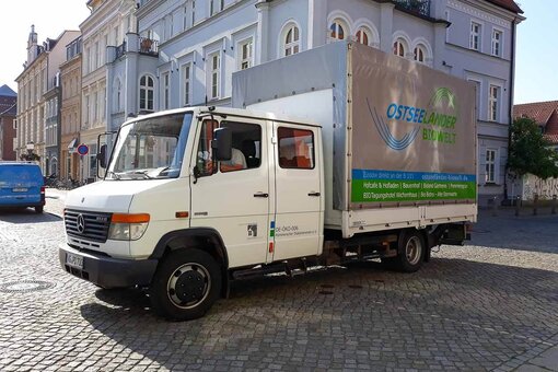 Ein LKW mit Aufschrift Ostseeländer Biowelt steht vor Gebäuden auf dem Greifswalder Marktplatz