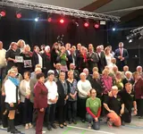 Eine Gruppe Menschen steht in zwei Reihen zusammen auf einer Bühne