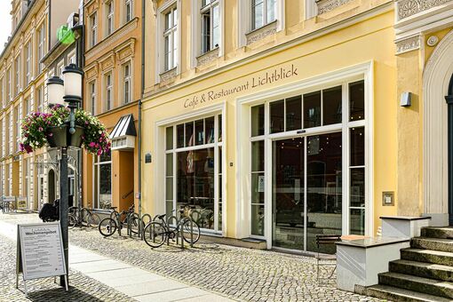 Außenansicht des Café und Restaurant Lichtblick vom Greifswalder Rathaus aus mit Aufsteller Mittagstisch und Blumenschmuck
