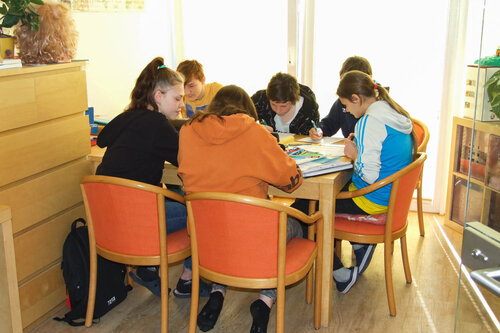 Eine Gruppe Jugendlicher sitzt an einem Tisch und arbeitet an den Schulaufgaben