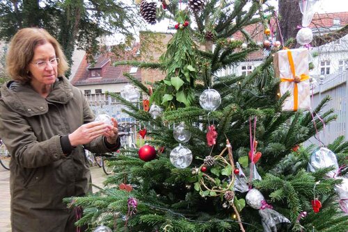 Eine Frau hängt einen Zettel an den Baum