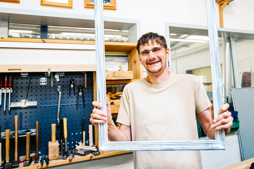 Ein Mann hält einen großen weißen Holzrahmen