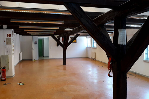 Ein großer leerer Raum, in dem große Holzstützen stehen und die hölzerne Decke stützen