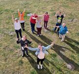 Eine Gruppe Menschen steht zusammen und hebt freuend die Arme in die Höhe