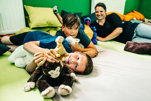 Zwei Jungs mit Kuscheltieren und ihre Betreuerin