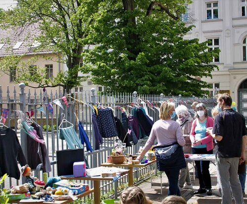 Menschen stehen vor verschiedenen gebrauchten Gegenständen, etwa Kleidung