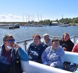 Eine Gruppe Menschen sitzt auf einem Schiff, das auf dem Wasser fährt.