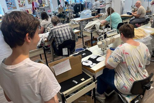 Eine Junge schaut auf die Arbeitstische in der Näherei