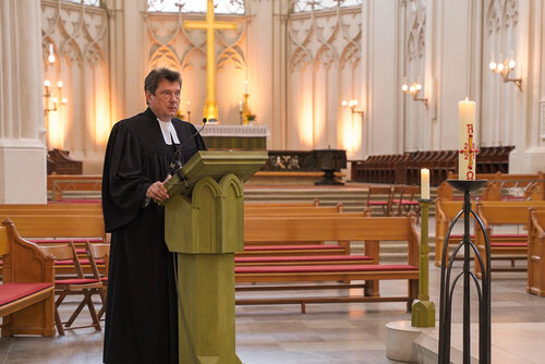 Pastor Dr. Michael Bartels spricht an einem Rednerpult vor leeren Sitzbänken im Greifswalder Dom