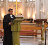 Pastor Dr. Michael Bartels spricht an einem Rednerpult vor leeren Sitzbänken im Greifswalder Dom