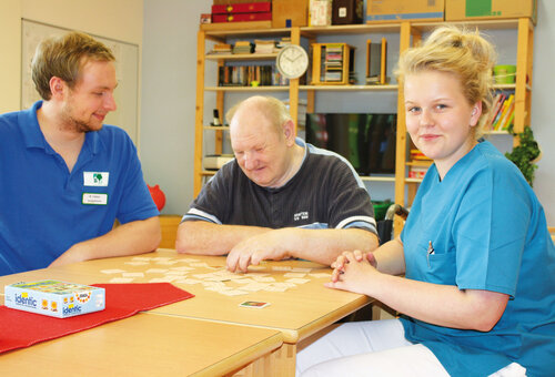 PDV-Mitarbeitenden am Tisch mit Kunden und Kartenspiel Drei Personen am Tisch