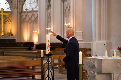 Ein Mann zündet eine große Kerze an.