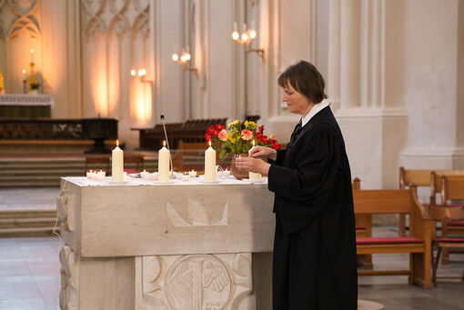 Eine Frau steht am Altar und entzündet Kerzen.