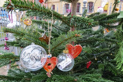 Ein Weihnachtsbaum mit vielen Kugeln und Wunschzetteln geschmückt