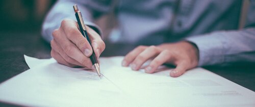 Stellenausschreibungen Eine Person unterschreibt mit einem Füller Papierzettel