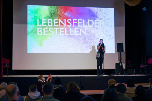 Eine Frau steht mit einem Mikrofon auf einer Bühne