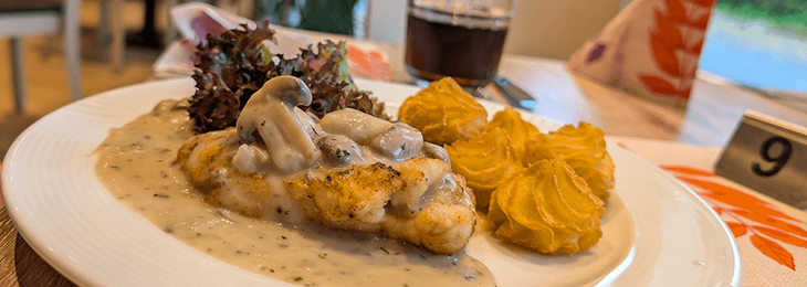 Ein Schnitzel mit Champions und Kartoffel-Kroketten und einer Sauce