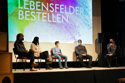 Auf einer Bühne sitzen fünf Menschen und unterhalten sich