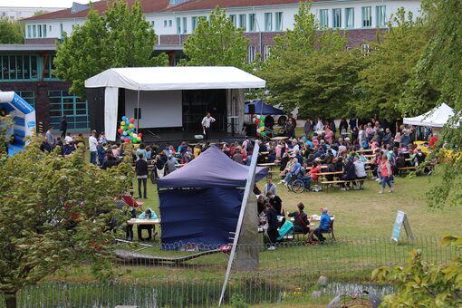 Ein großes Zelt mit Bierbänken und einer Bühne auf einer Wiese