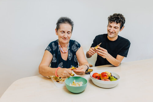 Zwei Personen schneiden Obst und Gemüse 