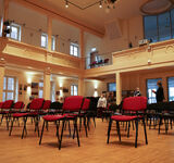 Ein großer Saal wie in einem Theater, in dem viele einzelne Stühle stehen